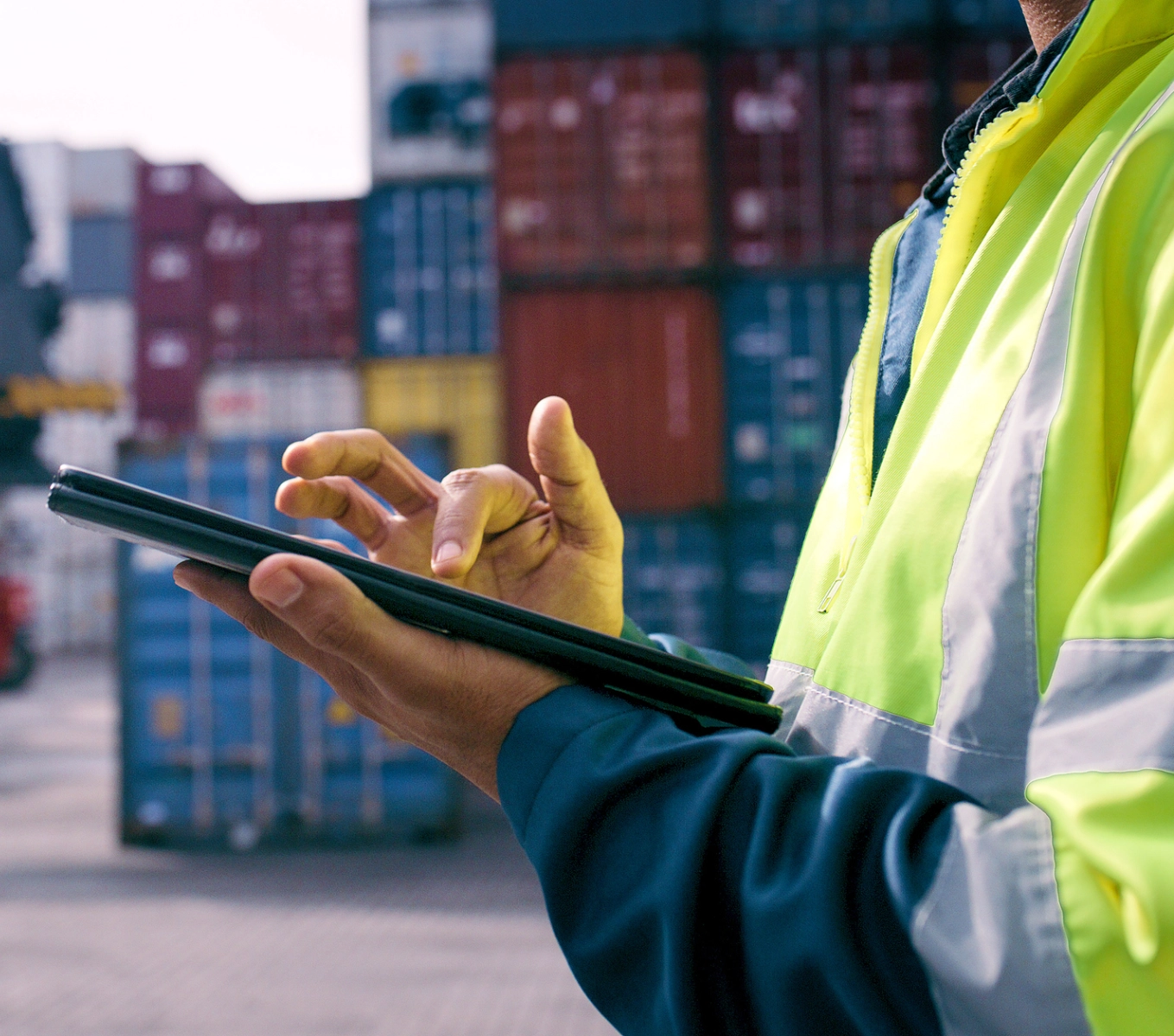 Worker using tablet near shipping containers.